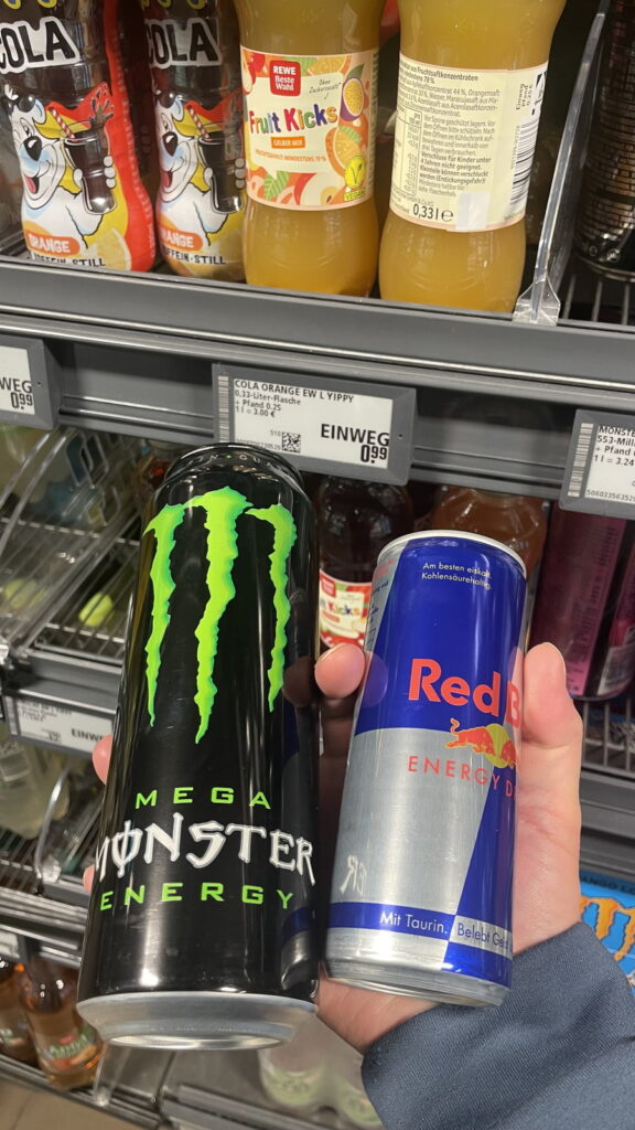 ドイツのスーパーの飲料棚。手前にエナジードリンクの缶を2本持っている